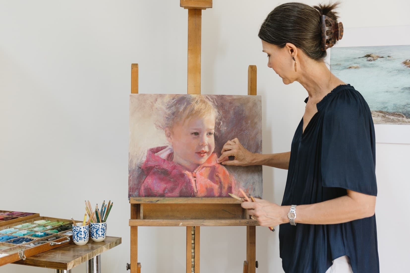 Karen Christiansen working on a pastel portrait at the easel in her studio